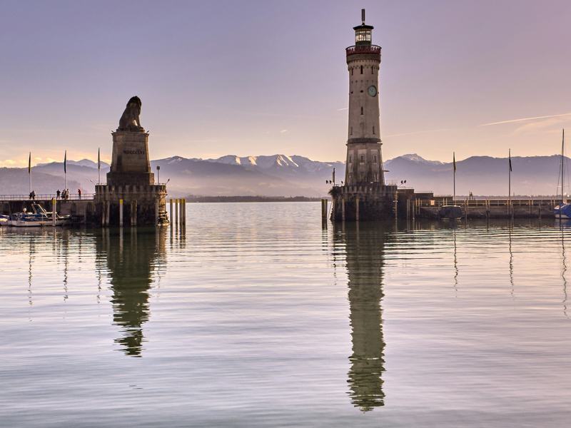Harbour entrance of Lindau with the lion monument and lighthouse reflected in the water